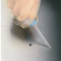 Une main applique de la colle provenant d''un flacon sur une vis.