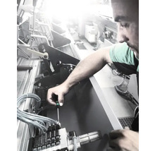 Ein Mann arbeitet mit einem Schraubendreher an einer Maschine.