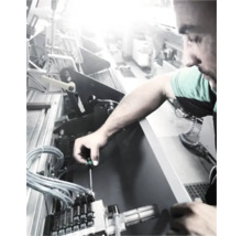 Un homme répare une machine avec un tournevis.