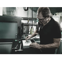 Ein Mann arbeitet an einem Werkstück mit Schraubendrehern in einer Werkstatt.