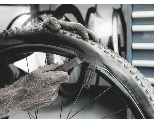 Nahaufnahme eines Fahrradreifens, der mit Reifenhebern montiert wird