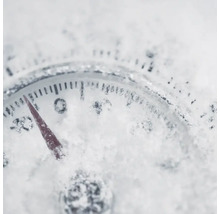 Ein Thermometer ist mit Schnee bedeckt und zeigt eine Temperatur unter dem Gefrierpunkt an.