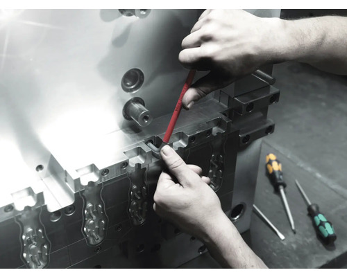 Ein Arbeiter führt mit einem Schraubendreher Wartungsarbeiten an einem Metallwerkzeug durch.