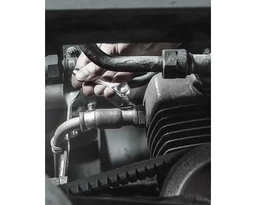 Hand schraubt Schraube an Motor mit Ratschenschlüssel fest