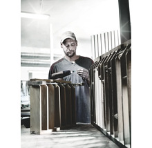 Artisan travaillant avec une perceuse sans fil sur un objet en bois dans un atelier.