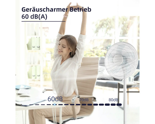 Eine Frau sitzt entspannt am Schreibtisch neben einem leisen Standventilator