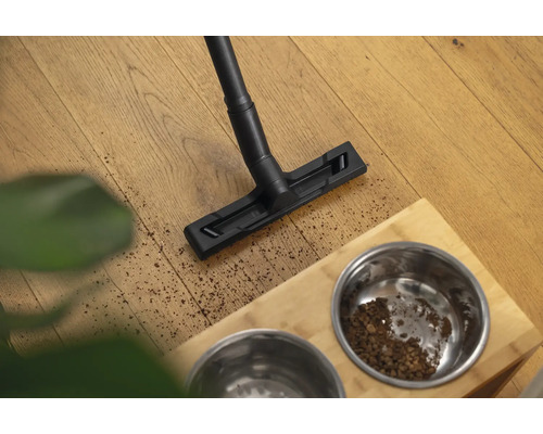 Aspirateur nettoyant le sol près d''une gamelle pour animaux