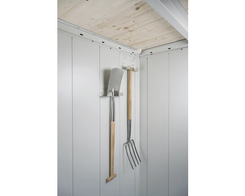 Une pelle et une fourche à foin avec manche en bois sont accrochées au mur