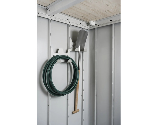 Tuyau d''arrosage et bêche sur un support sur un mur gris
