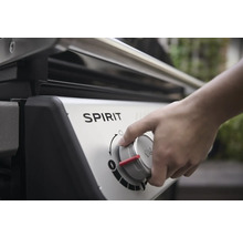 Gros plan d''un barbecue à gaz Spirit où une main actionne un bouton.