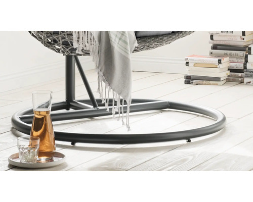 Nahaufnahme vom Fuss eines Hängekorbsessels mit Getränkekaraffe und Glas