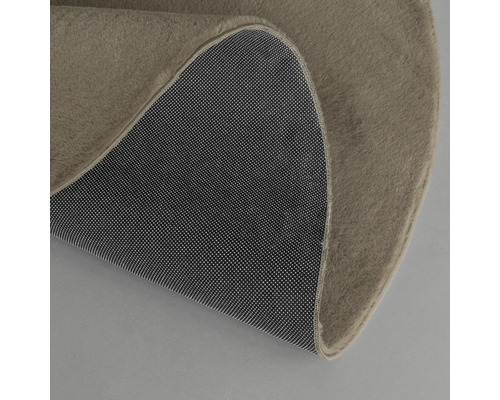 Detailansicht eines runden Teppichs mit Textiloberfläche und rutschfester Unterseite