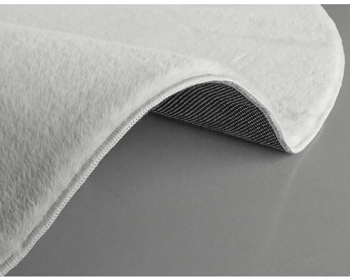 Detailansicht eines weißen Teppichs mit Flor und gewebter Rückseite