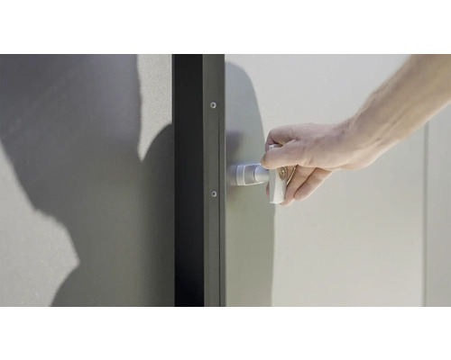 Une main actionne la poignée de porte sur une porte en acier