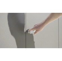 Un homme actionne un loquet de porte d''armoire sur une armoire grise.