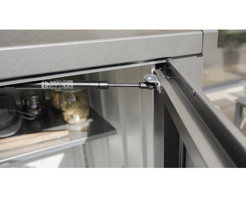 Detailansicht einer Gasdruckfeder an einem Gartenschrank