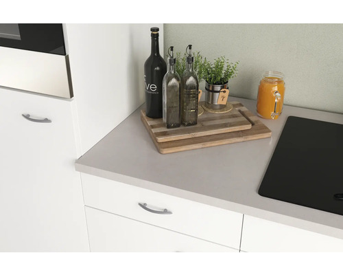 Nature morte de cuisine avec planches à découper, bouteilles d''huile, herbes et un verre de jus sur un plan de travail.