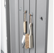 Gartengeräte wie eine Handschaufel und eine Bürste hängen an Haken in einem Geräteschuppen.