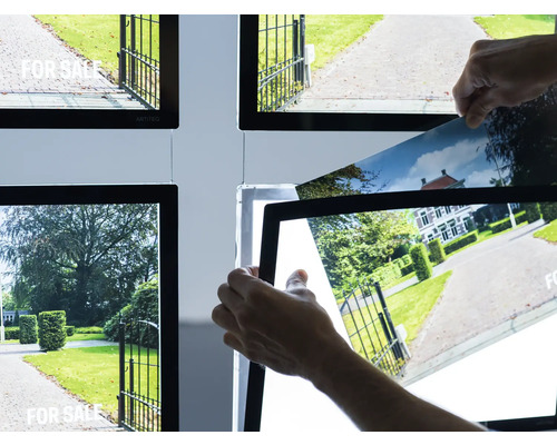 Leuchtrahmen mit Immobilienanzeigen und Hände beim Austauschen eines Bildes