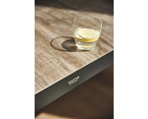 Glas Waasser mat Zitroun op engem Gaartdësch vun der Mark Siena Garden.