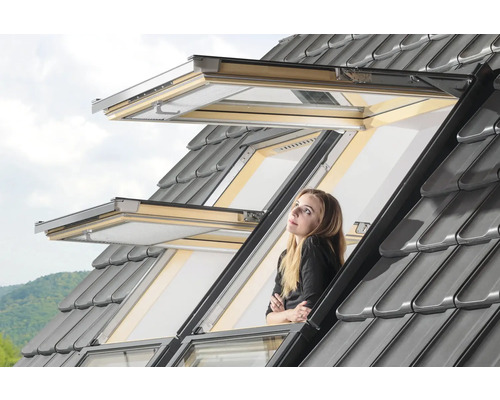 Femme regardant par une fenêtre de toit ouverte avec des tuiles grises