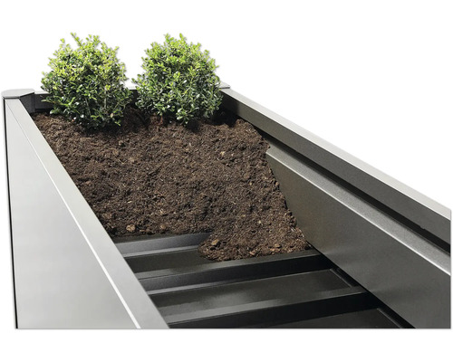 Gros plan d''une jardinière en métal plantée avec de la terre et des plantes.