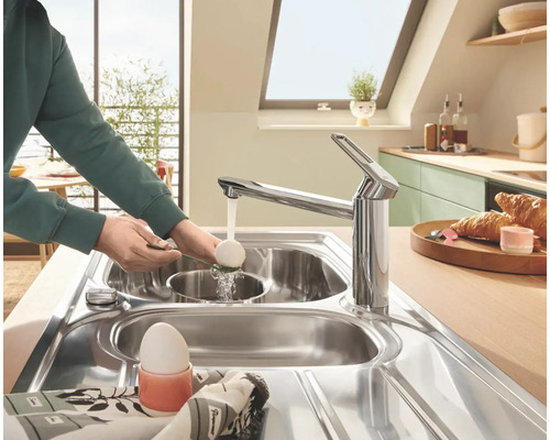 Küchenszene mit Spültischarmatur, Spüle und Person beim Abwaschen eines Eis