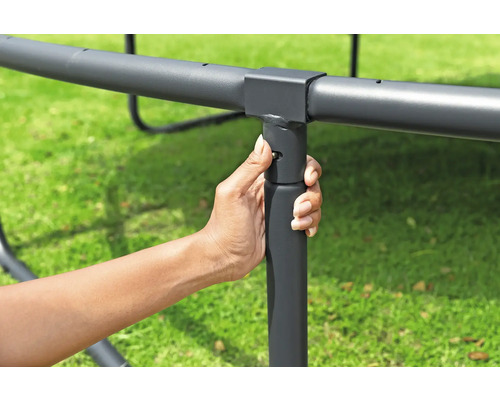 Une main fixe un pied de trampoline au cadre.