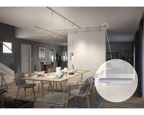 Salle à manger avec table et rail de plafond avec spots et suspensions.