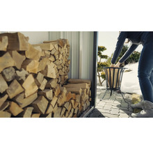 Frau befüllt Feuerkorb mit Holz aus einem Holzregal