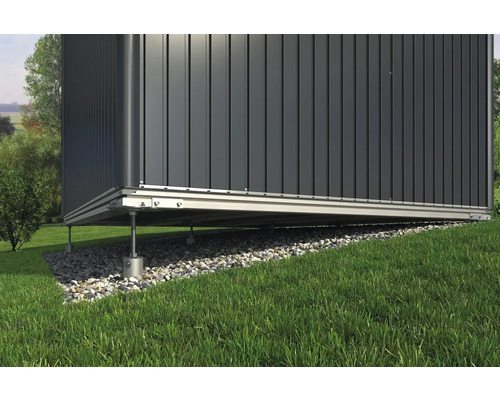 Detailansicht eines Gartenhauses mit Fundament auf einem Rasenhang.