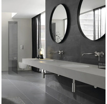 Salle de bains moderne avec double vasque, miroirs ronds et mur de carreaux gris.