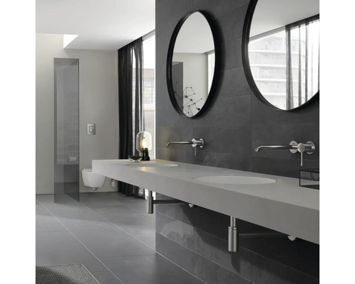 Salle de bains moderne avec double vasque, miroirs ronds et mur de carreaux gris.