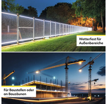 Beleuchteter Zaun für den Aussenbereich und Baustellenbeleuchtung mit Kränen im Hintergrund