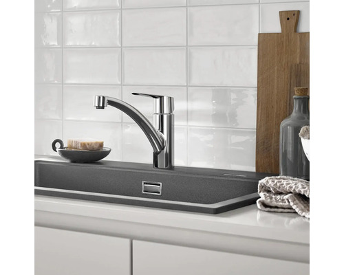 Küchenszene mit Spültischarmatur, Spülbecken und Küchenutensilien.