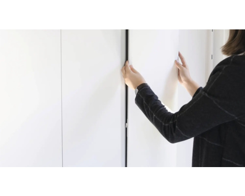 Eine Person montiert eine Schiebetür an einem Schrank.