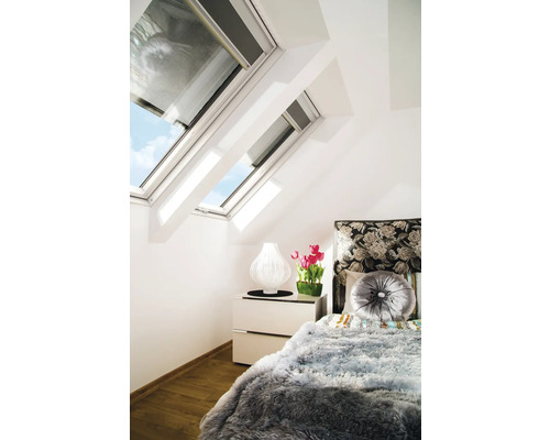 Chambre avec fenêtres de toit, lampe de chevet, tulipes et un lit avec des coussins