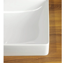 Vue détaillée d'un lavabo à poser rectangulaire en céramique blanche sur une surface en bois.
