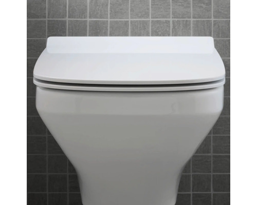Gros plan de toilettes blanches avec couvercle fermé devant un mur gris