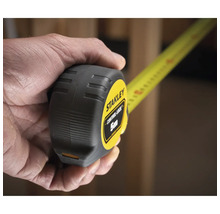 Une main tient un mètre à ruban Stanley d'une longueur de 5 mètres.