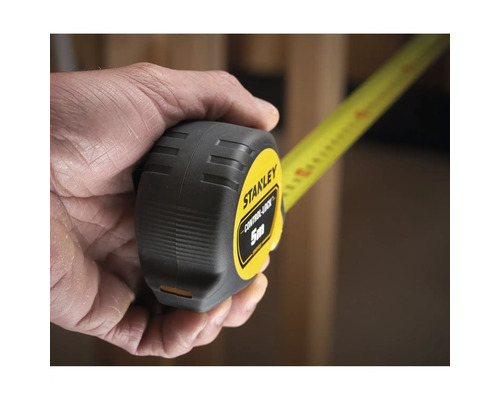 Une main tient un mètre à ruban Stanley d'une longueur de 5 mètres.