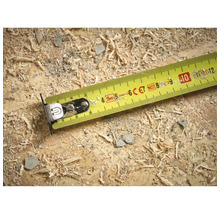 Ruban à mesurer jaune sur une surface en bois avec de la sciure