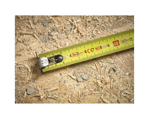 Ruban à mesurer jaune sur une surface en bois avec de la sciure