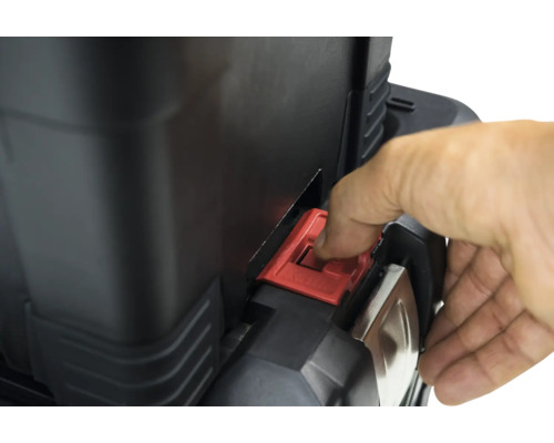 Detailansicht eines Werkzeugkoffers mit rotem Verschluss, der von einer Hand bedient wird.