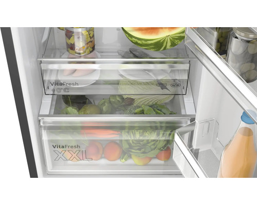 Innenansicht eines Kühlschranks mit Gemüsefächern und verschiedenen Lebensmitteln wie Gemüse und Obst