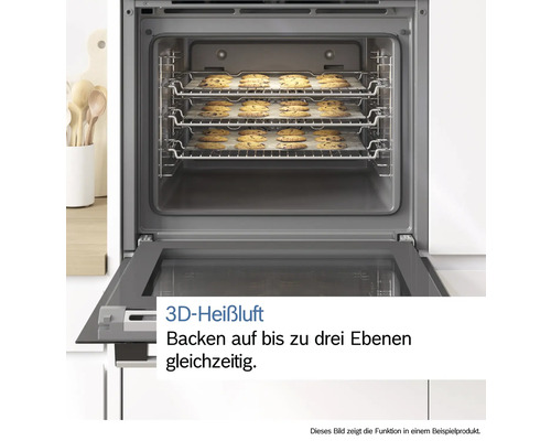 Geöffneter Backofen mit drei Ebenen Schokostückchen-Keksen auf Backpapier