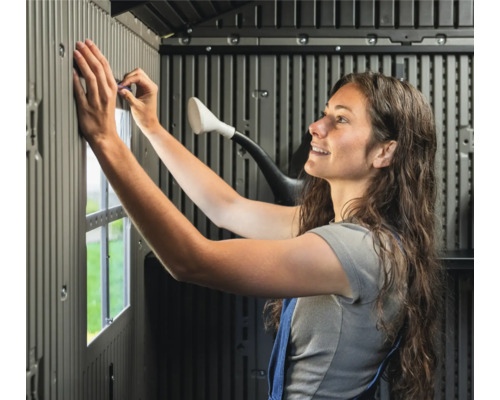 Frau montiert ein Gartenhaus aus Kunststoff