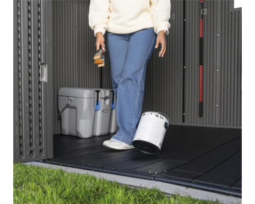 Innenansicht eines Gartenschuppens mit Bodenfliesen, Farbeimer und Kühlbox