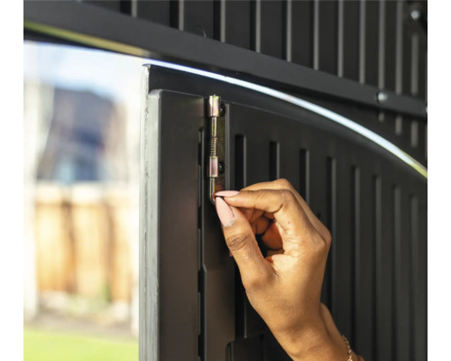 Eine Person betätigt einen Riegel an einer Gartentür zur Sicherung.