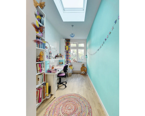 Heller Raum mit Schreibtisch, Bücherregal, Dachfenster und rundem Teppich
